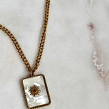 Iridescent Sun Necklace with 18K gold plated stainless steel chain and square sun pendant on marble background