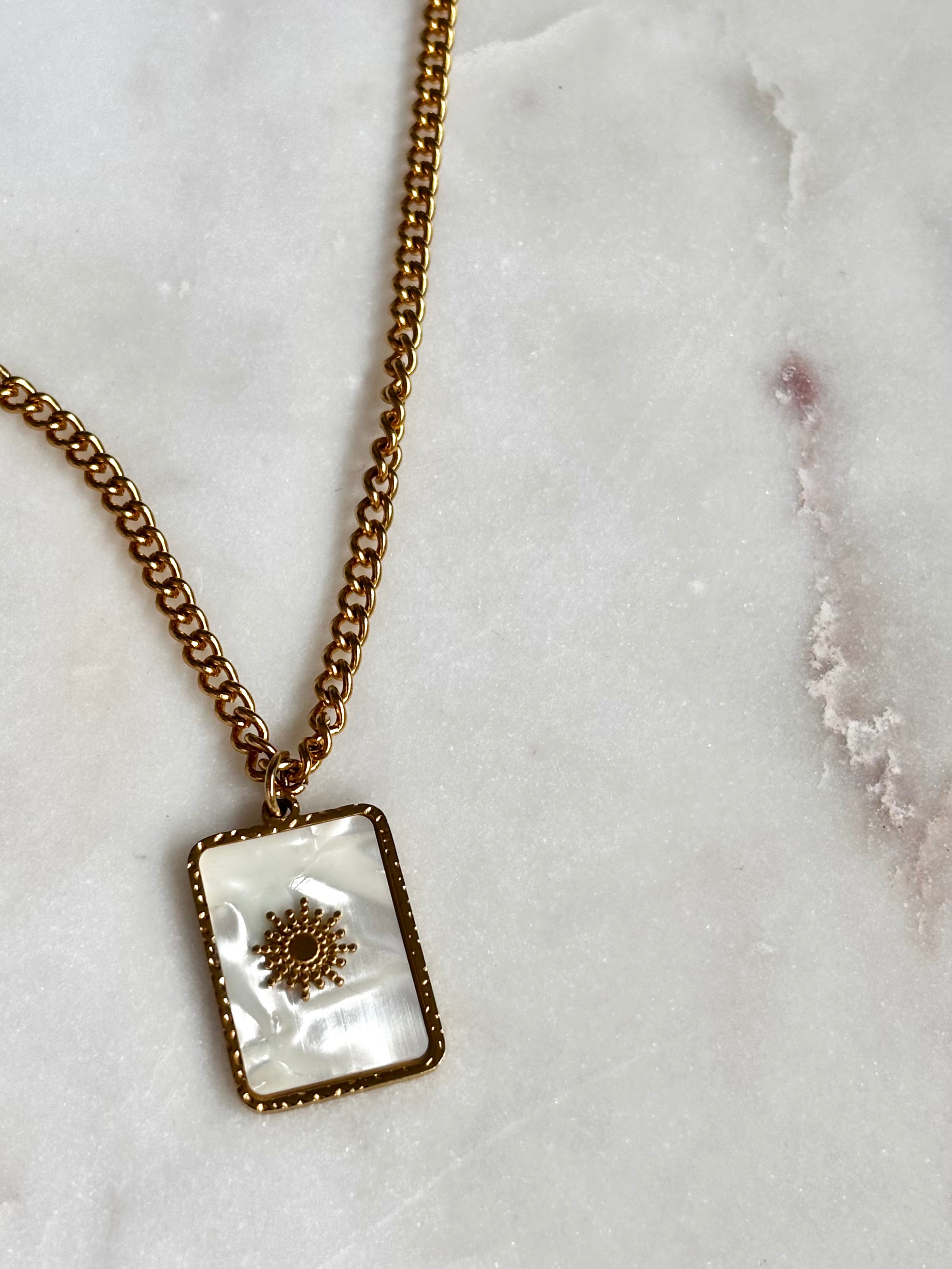 Iridescent Sun Necklace with 18K gold plated stainless steel chain and square sun pendant on marble background